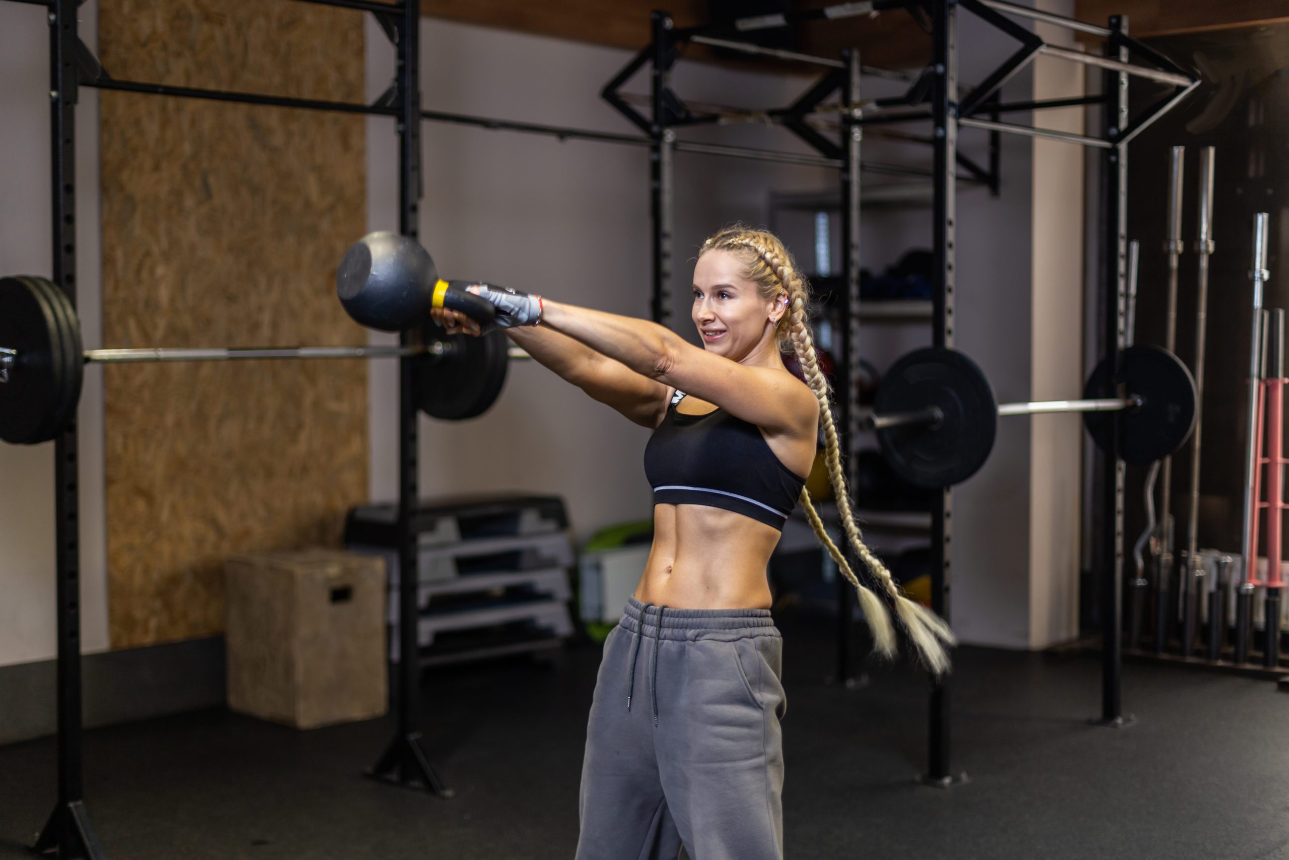 Fit woman works out with heavy kettlebell in modern gym. Functional muscle training with the kettlebell swing.