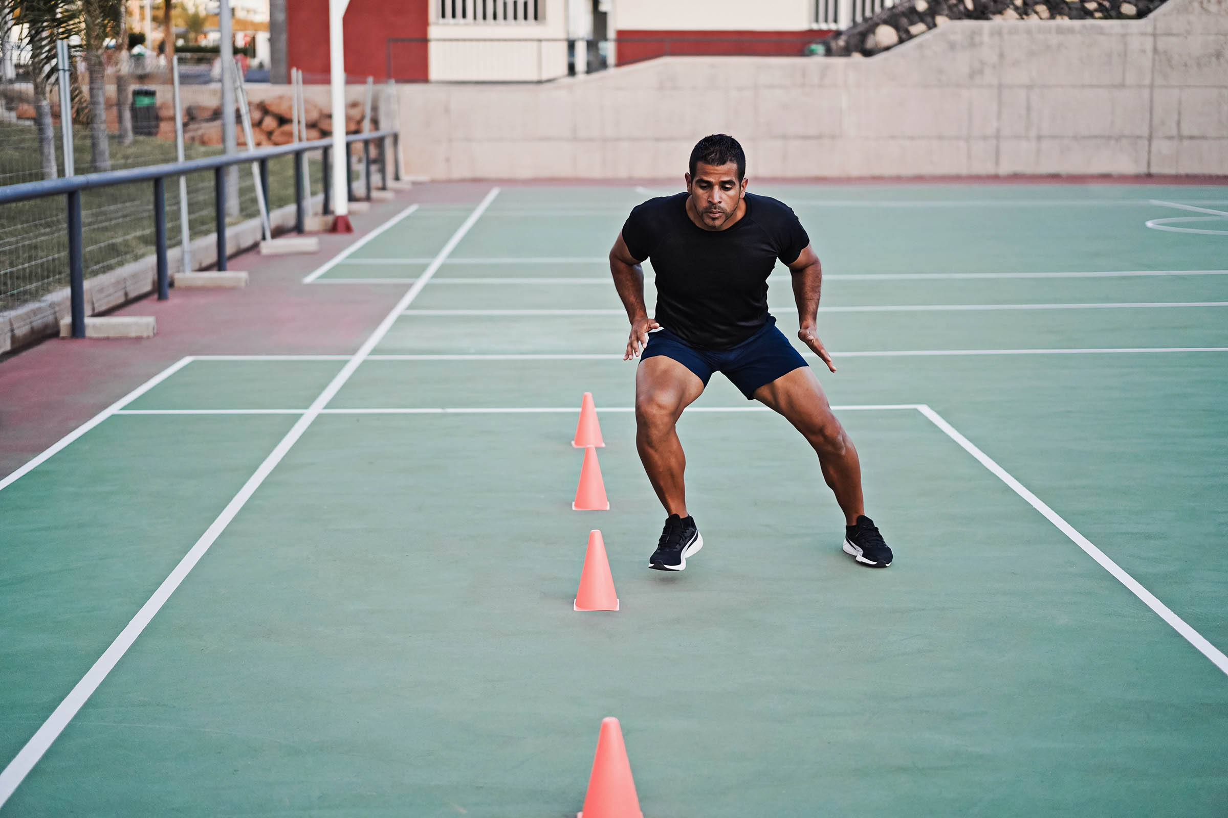 Man working on deceleration skills by doing speed and agility cone drills workout session outdoors.