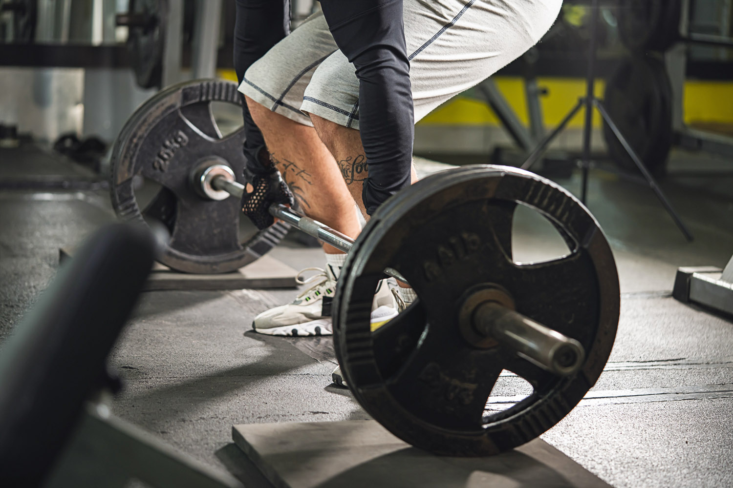 Side view of man holding barbell weight grip at gym lifting weights in training dead-lift position