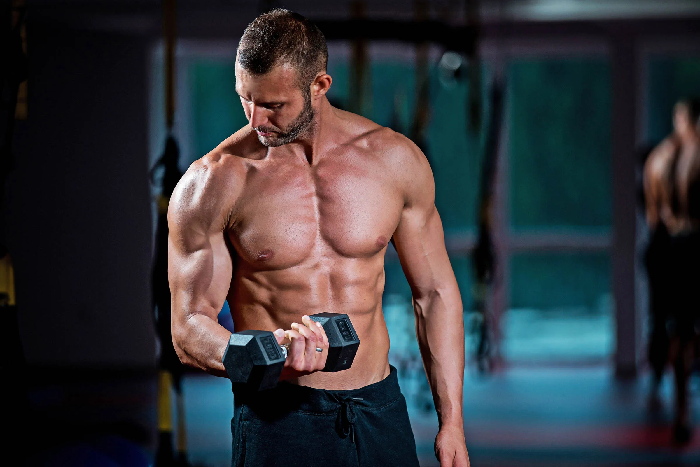 Muscular vegan athlete building muscle at the gym doing a bicep curl